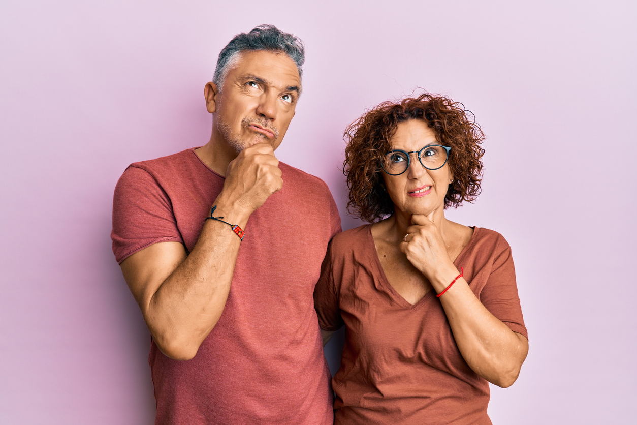 Beautiful middle age couple together wearing casual clothes thinking worried about a question, concerned and nervous with hand on chin about affordable Exterior & Interior Painting.