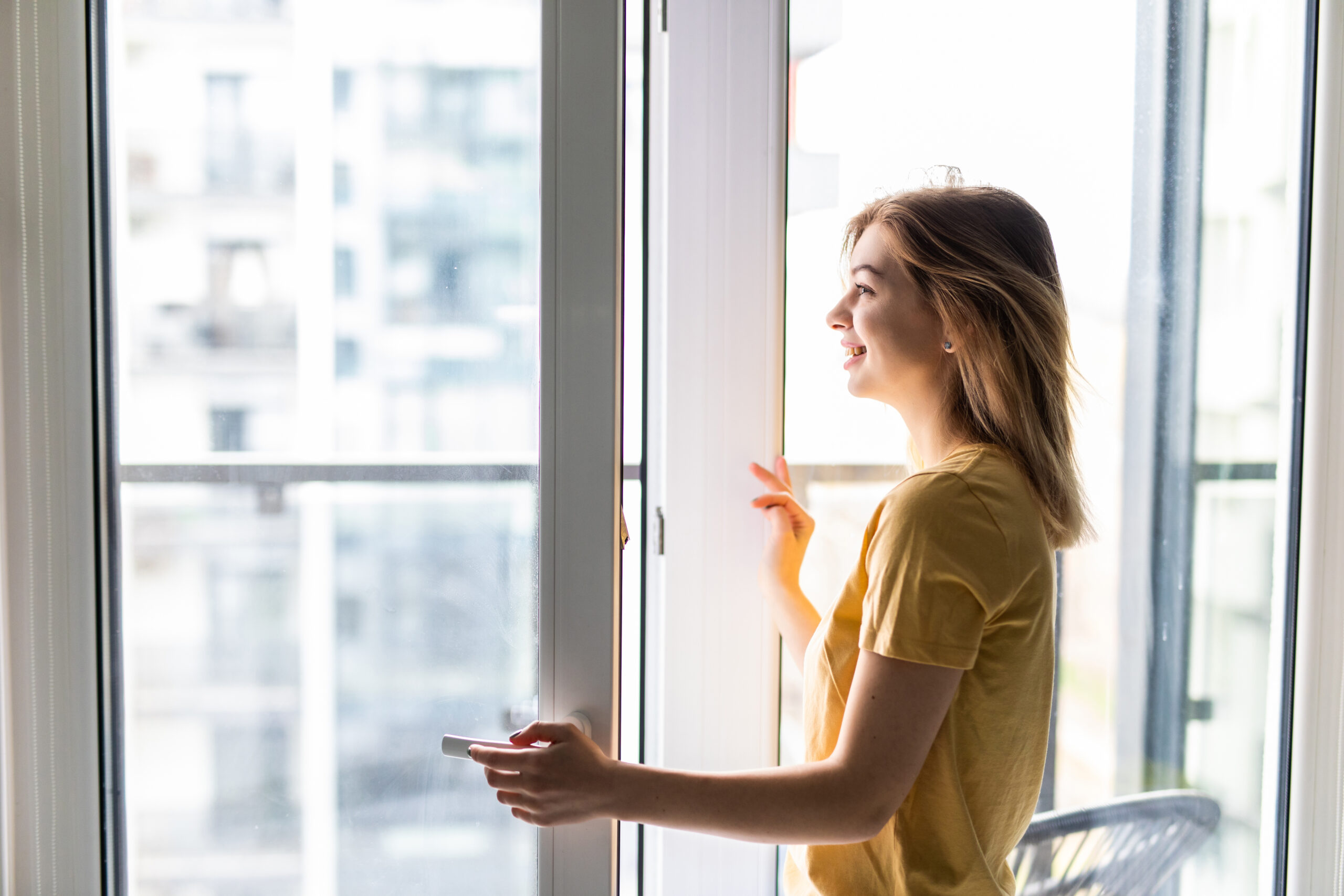 Young woman opening affordable Hurricane Windows in living room.