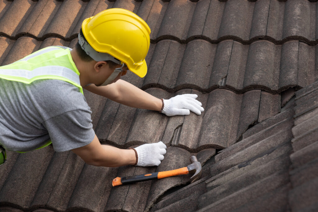 Worker man replace tile of the old roof.